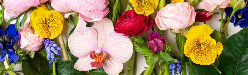 Flowers composition made of roses, ranunculus, pansies and orchids flowers background. Flat lay, top view floral scene.