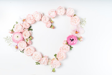 Floral composition. Heart frame made of pink rose and ranunculus flowers on white background. Flat lay, top view, copy space