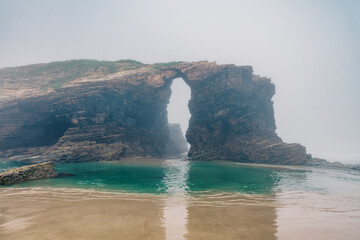 Cathedrals beach in Galicia, Spainn. Foggy landscape with Playa de Las Catedrales Catedrais beach in Ribadeo, Lugo on Cantabrian coast. Natural archs of Cathedrals beach. Moody rock formations - 779530704