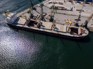 Aerial view of big cargo ship bulk carrier is loaded with grain of wheat in port at sunny day