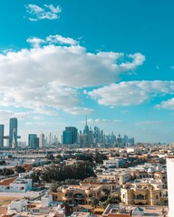 Fototapeta premium Vertical shot of the Dubai skyline under a blue sky with clouds.