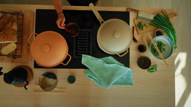 Overhead shot of kitchen counter with induction stove and integrated extractor fan, woman cook delicious asian dish, dim sum and green vegetables, steamed in a pan. Inspiring cooking at home