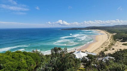 Landscape of Sugar Loaf Point beach surrounded by the sea and greenery in Australia