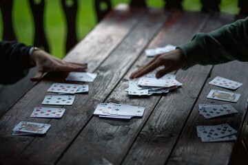 People playing French cards on a wooden table in a lovely park on a sunny day