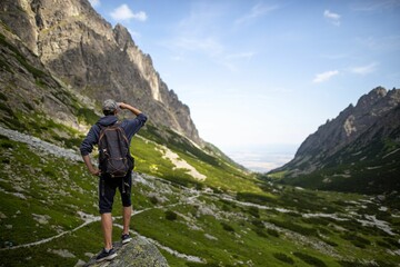 Fototapeta premium Low-angle shot of little Tarpataki valley with a man's rear view walking, blue sky in the background