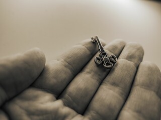 Closeup grayscale of a vintage metal key on the palm of a person on an isolated background