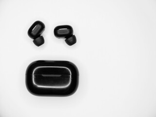 Top view grayscale of wireless earbuds with a black powerbank on an isolated background