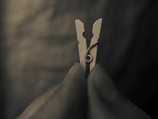 Macro grayscale of a person holding a wooden clothespin between his fingers
