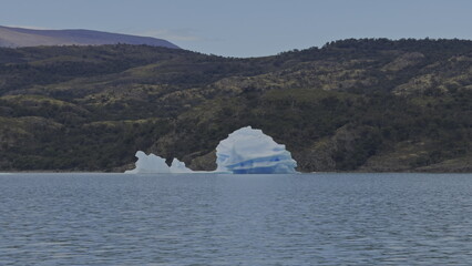 Enormous Iceberg Adrift Close to Shore in Lush Lake Landscape