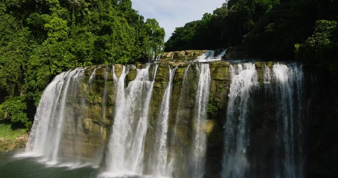 Drone view of white water curtain-like of Tinuy an Falls with rainbow. Bislig, Surigao del Sur. Philippines.