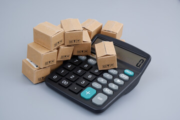 Fototapeta premium Cost of goods, taxes and shipment concept. Many carton boxes and calculator.