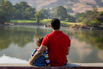 isolated young father and son enjoying nature at morning with blurred background