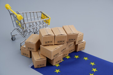 Shopping in European Union concept. Shopping cart, many carton boxes and EU flag.	