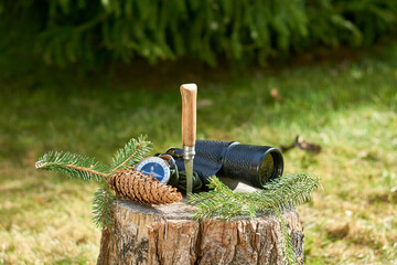 A rustic knife with a wooden handle, a vintage monocular, a handheld compass, and a pine branch...