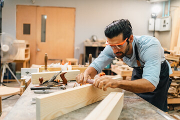 Carpenter working with electric planer on wooden plank in workshop. Craftsman makes own successful small business, man using tool in carpenter's shop to making a furniture from wood