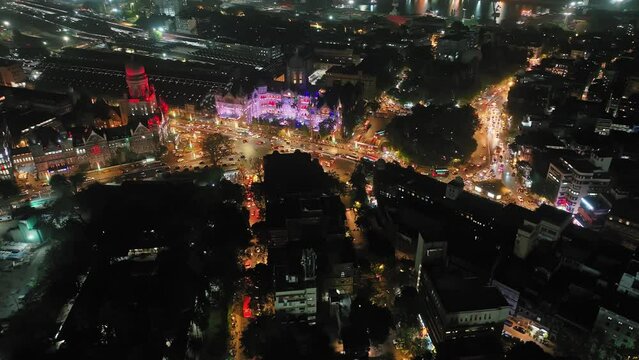 Aerial view of a busy road intersection in front of Chhatrapati Shivaji Maharaj Terminus train station in Mumbai, Traffic at CST Station. Shot of Mumbai Skyline, high-rise buildings in South Mumbai. 