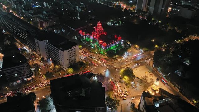 Aerial footage of traffic congestion at Church Gate station with colorful lighting of the Indian flag in the background and a view of the Mumbai skyline featuring high-rise buildings in South Mumbai