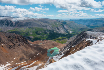 Vast top view from snow cornice on rocky precipice edge to most beautiful turquoise glacial lake...