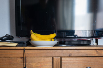 Fresh ripe banana fruit on table next to tv