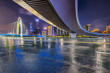Asphalt road and bridge with modern city buildings scenery at night in Guangzhou. Road and city buildings background after rain.