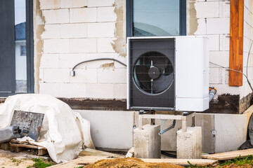 Air source heat pump installed outside of new and modern house under construction