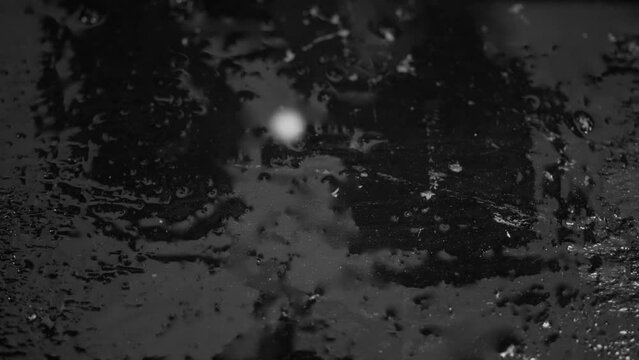 Reversed footage captures a white droplet striking the surface and dispersing, embodying an artistic concept.