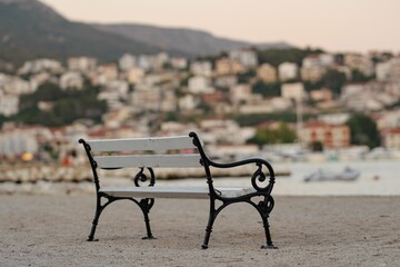 Beautiful shot of a bench on a shore with the background of the Stobrec cityscape