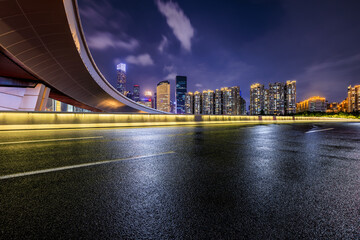 Asphalt highway road and bridge with city buildings at night