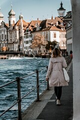Fototapeta na wymiar Vertical shot of a woman walking in Lucerne with Jesuit Church in the background, Switzerland