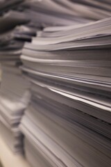 Vertical shot of a stock of white papers on the blurred background