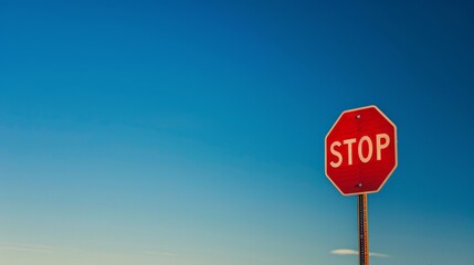 Vibrant stop sign against clear blue sky - obrazy, fototapety, plakaty