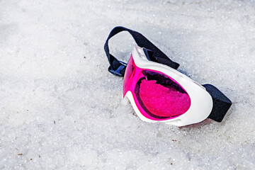 pink lying mask lies on a wet snowy slope on a sunny day. Winter snow season. Active holiday with family