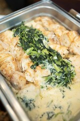 Closeup shot of chicken meat in the sauce with herbs on it served at a cafeteria