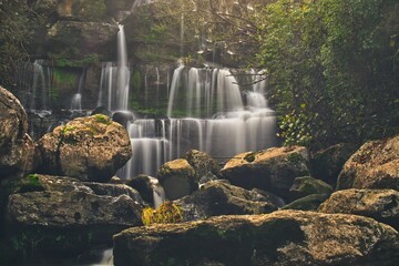 Scenic shot of huge stones behind the cascades of waterfalls, long exposure photography