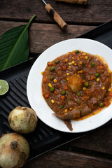 Vertical high angle shot of a bowl of vegetable stew with corn and peas on a messy table
