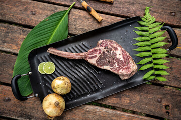 Piece of raw beef steak on a bone with herbs and spices from above