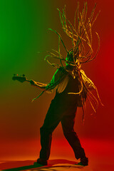 Young energetic musician with long dreadlocks playing electric guitar with passion and energy...