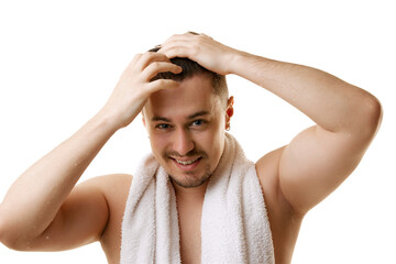 Portrait of man strokes and styles his hair after shower looking at camera against white studio...