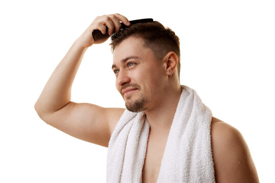 Portrait of man styles his hair with comb after shower looking at camera against white studio background. Concept of natural beauty, male health, anti-aging, spa procedures, cosmetic products.