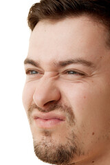 Close up photo of young brunette man with stubble grimacing against white studio background. Anti-aging cosmetology procedures Concept of natural beauty, male health, spa procedures, cosmetic product.