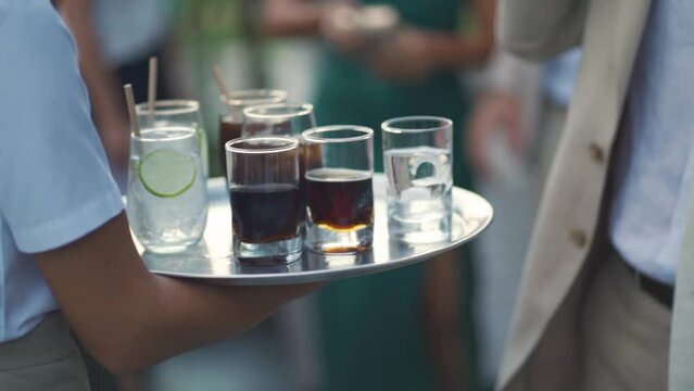 Waitress passes a tray of drinks between a group of people during a wedding party