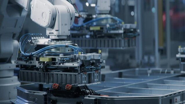Close-up of Automated Lithium-Ion EV Battery Pack for Automotive Industry Manufacturing Line with White Robotic Arms. Electric Car Assembly Smart Factory. Production Line with Robot Arms