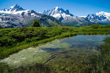 Fototapeta na wymiar Landscape of a lake with grass fields in charamillon gondola snowy alps in Haute Savoie, France