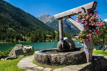 Scenic shot of a fountain decorated with pink flowers in a waterfront park in Valais, Switzerland