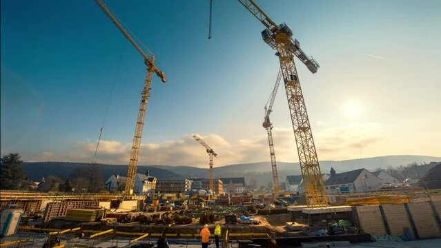 Time-lapse footage of a large construction site with several busy cranes in nice morning light, with emerging and dissolving clouds

