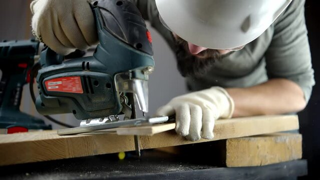 Carpenter sawing wood with electric jigsaw	