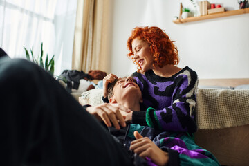 joyous appealing woman with red hair hugging lovingly her handsome cheerful boyfriend at home