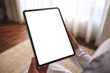 Mockup image of a woman holding digital tablet with blank desktop screen while sitting on a sofa at home - 779609123