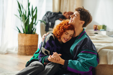 alluring cheerful couple in vibrant fashionable clothes hugging lovingly each other at home