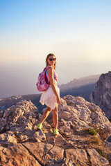 The young woman with backpacks hiking in the mountains at sunset